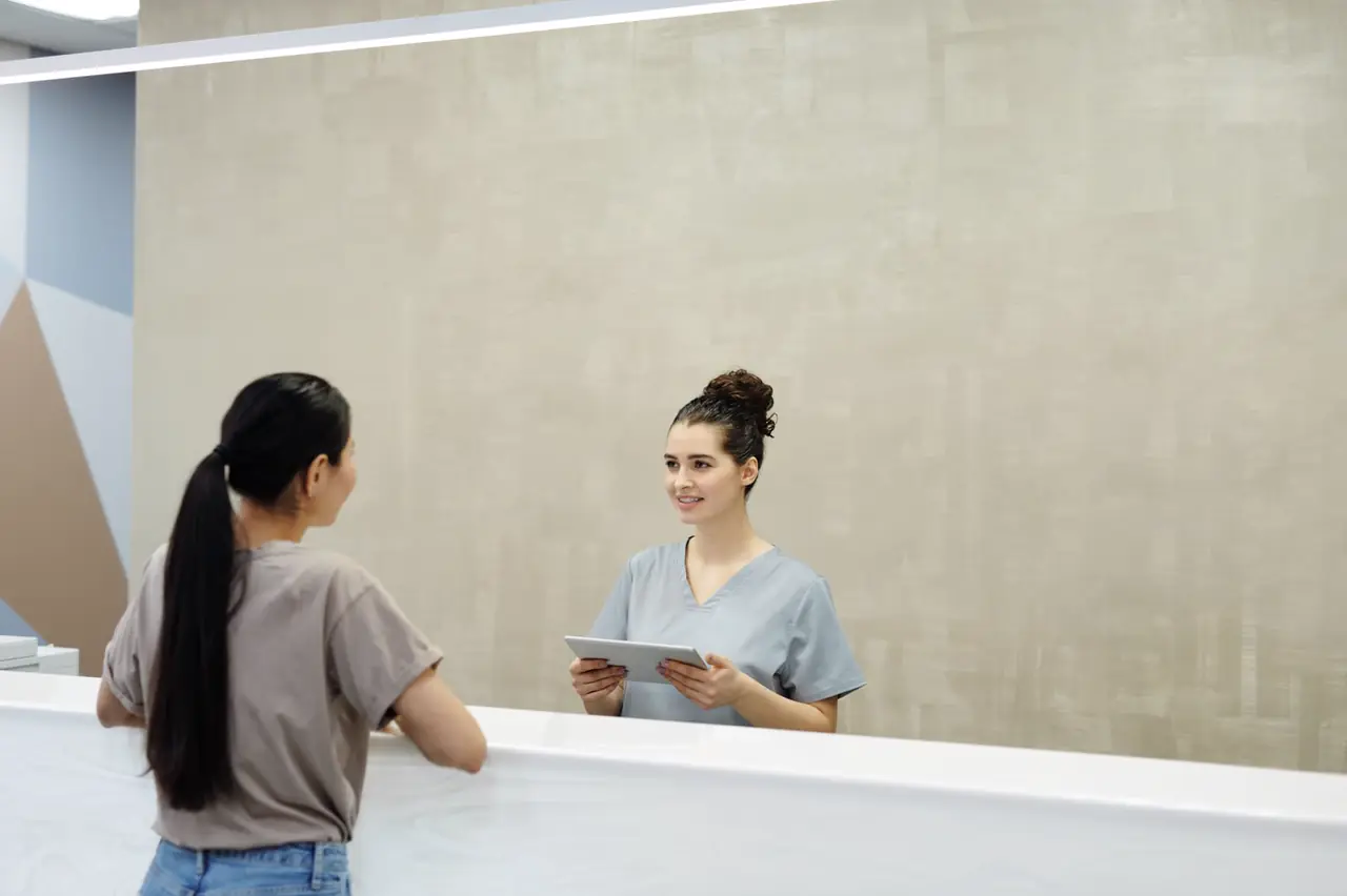 A calm clinic front desk with a tablet and a wall calendar.
